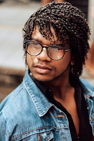 woman in blue denim jacket wearing black framed eyeglasses