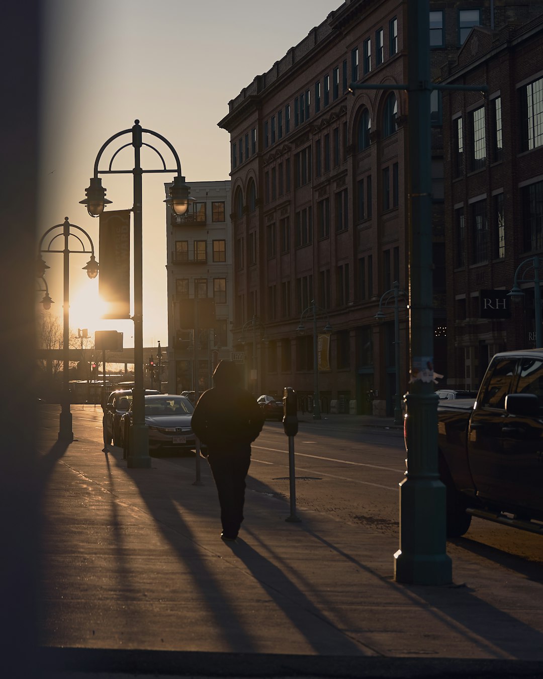 silhouette of man walking on sidewalk during night time