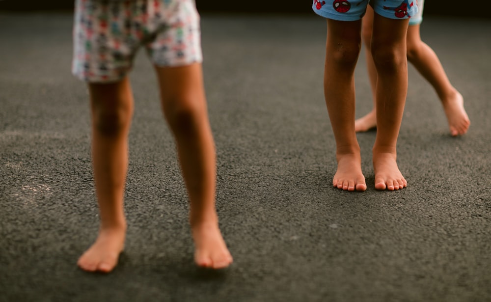 child in white and red shorts standing on gray concrete floor