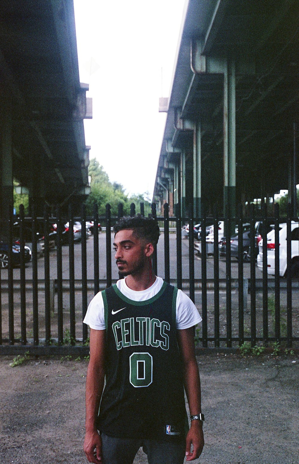 man in white and black crew neck t-shirt standing near black metal gate during daytime