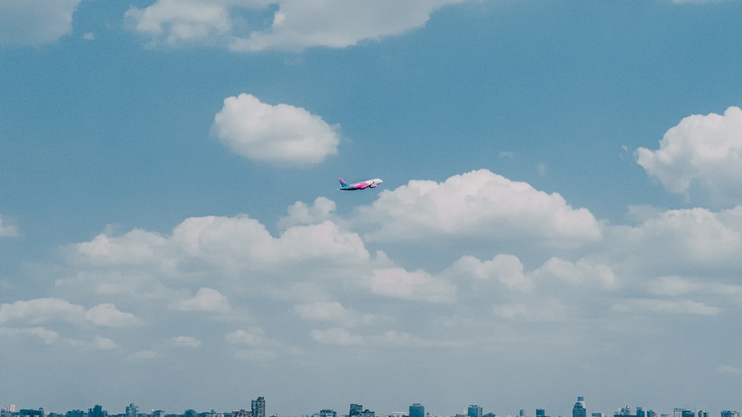 red and white plane flying over city during daytime