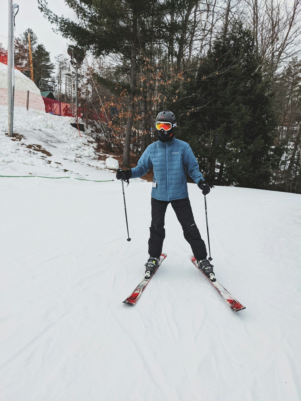 man in blue jacket and blue helmet riding on red ski blades on snow covered ground