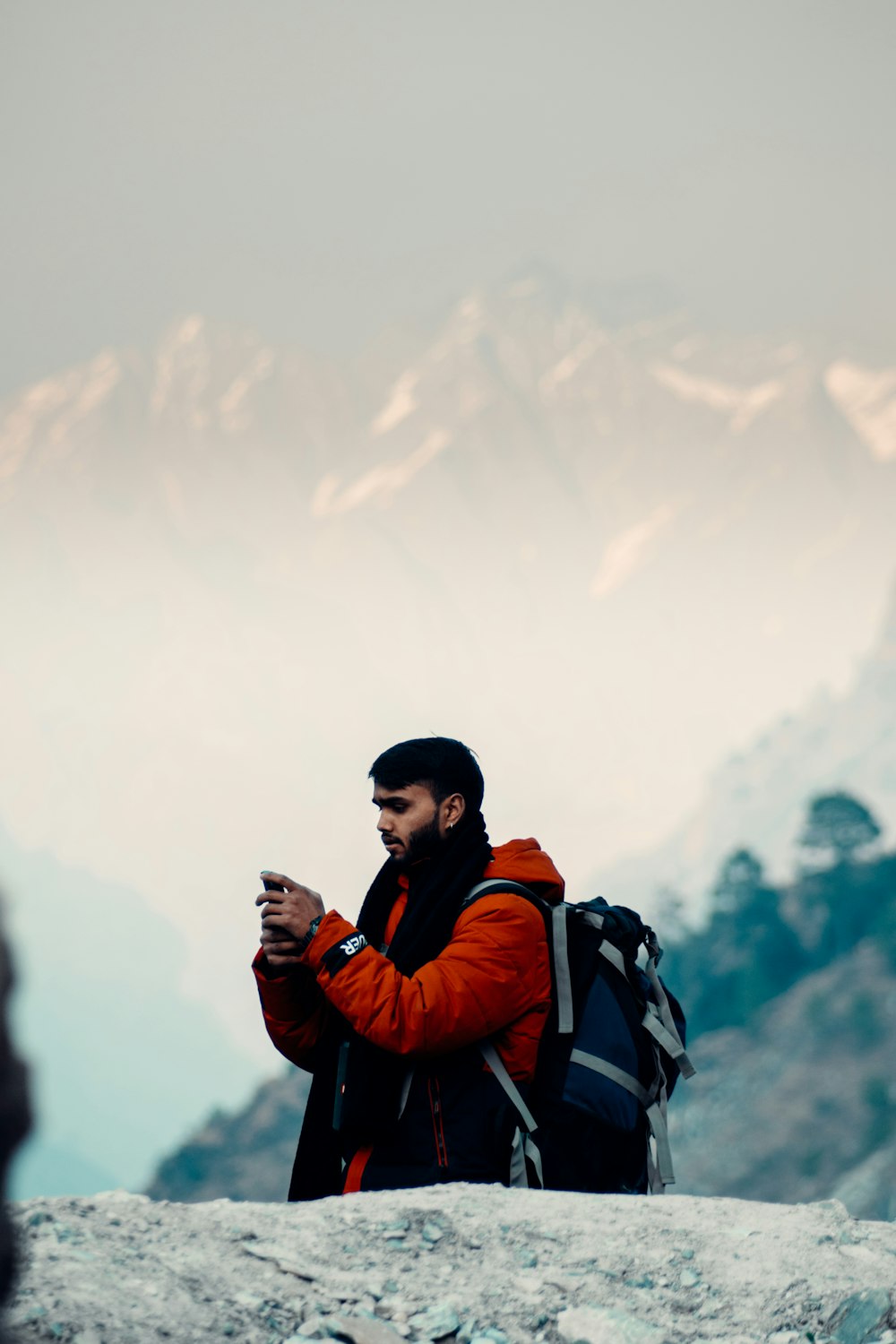 man in red and black jacket holding black smartphone