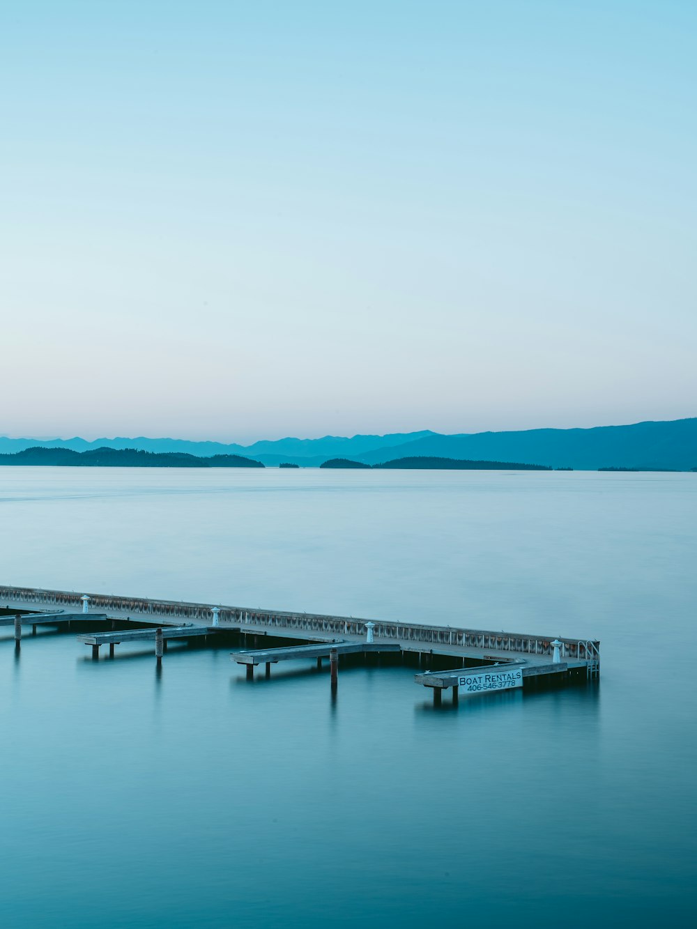 white wooden dock on blue sea under white sky during daytime