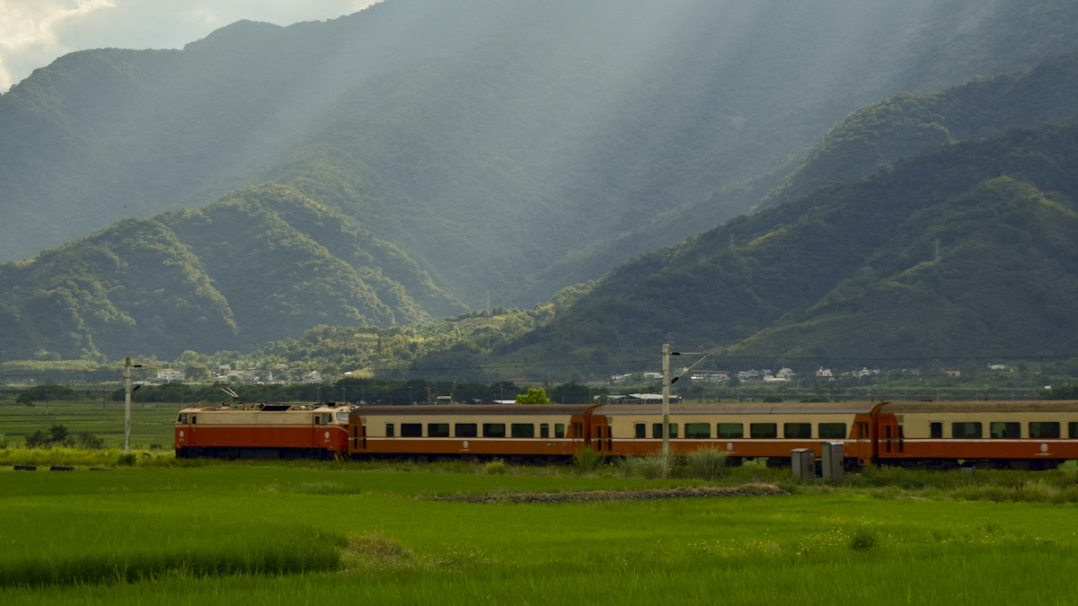 A TRA train passing rice fields in front of the mountains in eastern Taiwan
