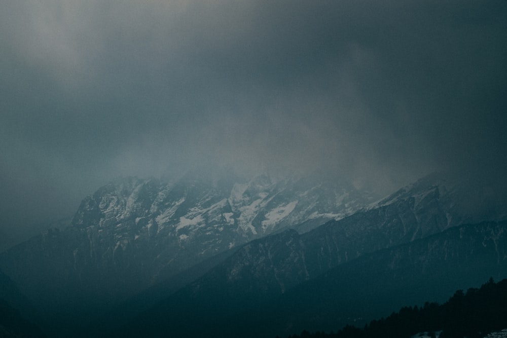 snow covered mountains under gray sky