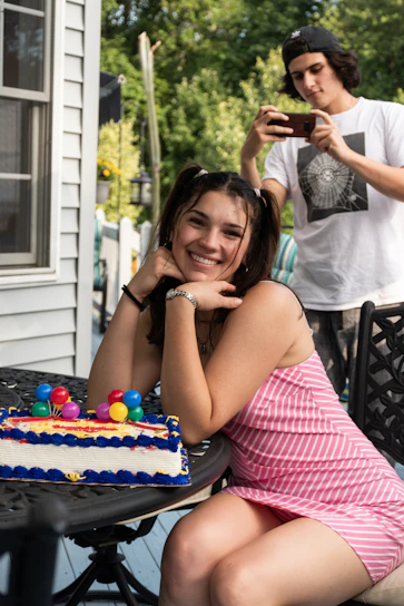 A joyful young woman in an elegant dress smiling during her 15th birthday photo session in a sunlit garden.