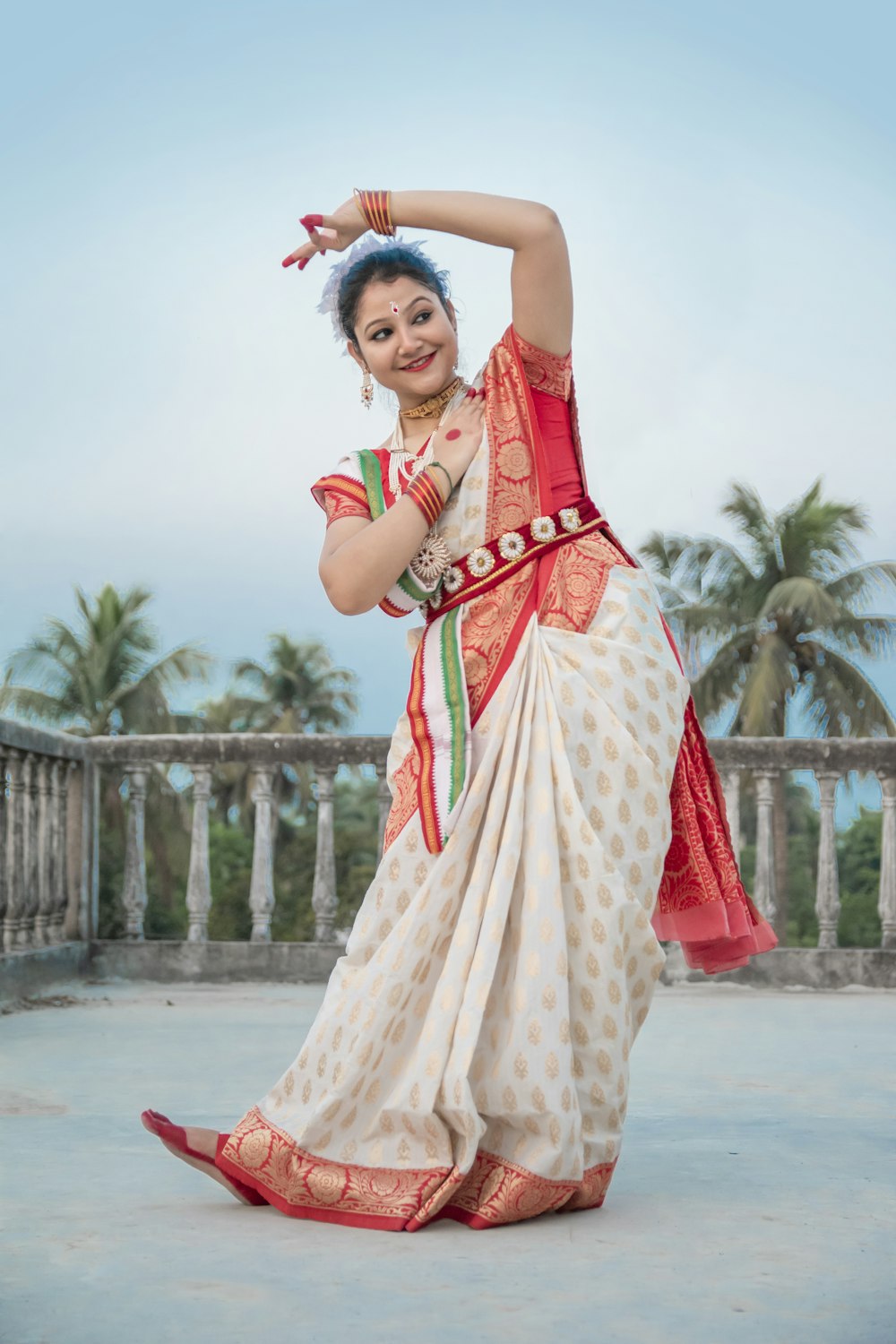 mulher em sari vermelho e branco de pé no chão de concreto cinzento durante o dia