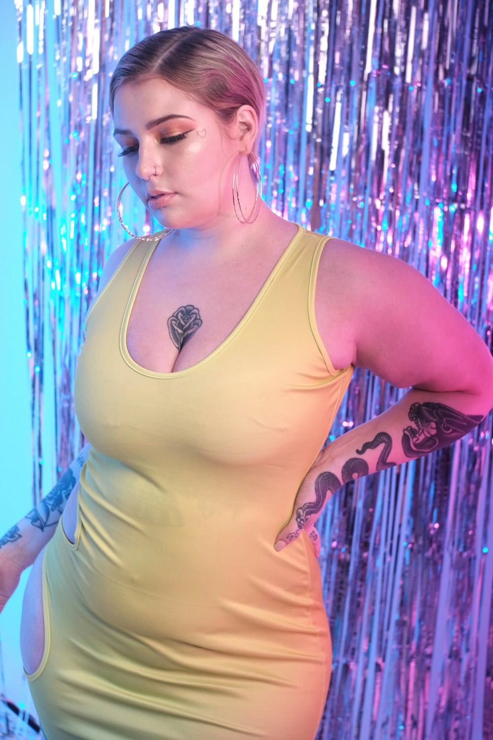 woman in white tank top standing beside blue and purple lights