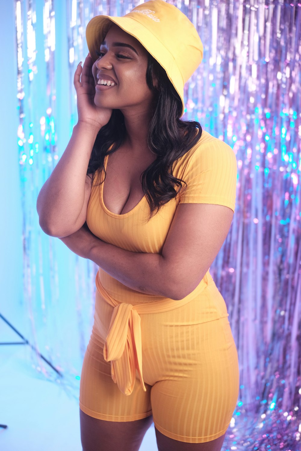 woman in yellow dress standing near blue and white floral curtain