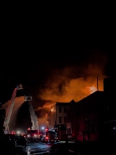 Firefighters in action battling a blaze in a residential neighborhood at dusk.
