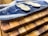A set of wooden cutting boards stacked on top of each other with unique grain patterns. On the top board, there is a decorative resin wave design in blue and white. Two small wooden sporks are placed on the resin surface.