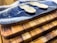 A set of wooden cutting boards stacked on top of each other with unique grain patterns. On the top board, there is a decorative resin wave design in blue and white. Two small wooden sporks are placed on the resin surface.