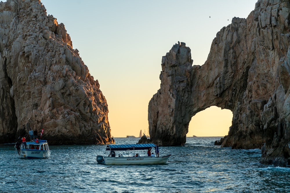 white and blue boat on sea near brown rock formation during daytime