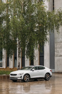 A sleek corporate sedan parked outside a modern office building during morning rush hour.
