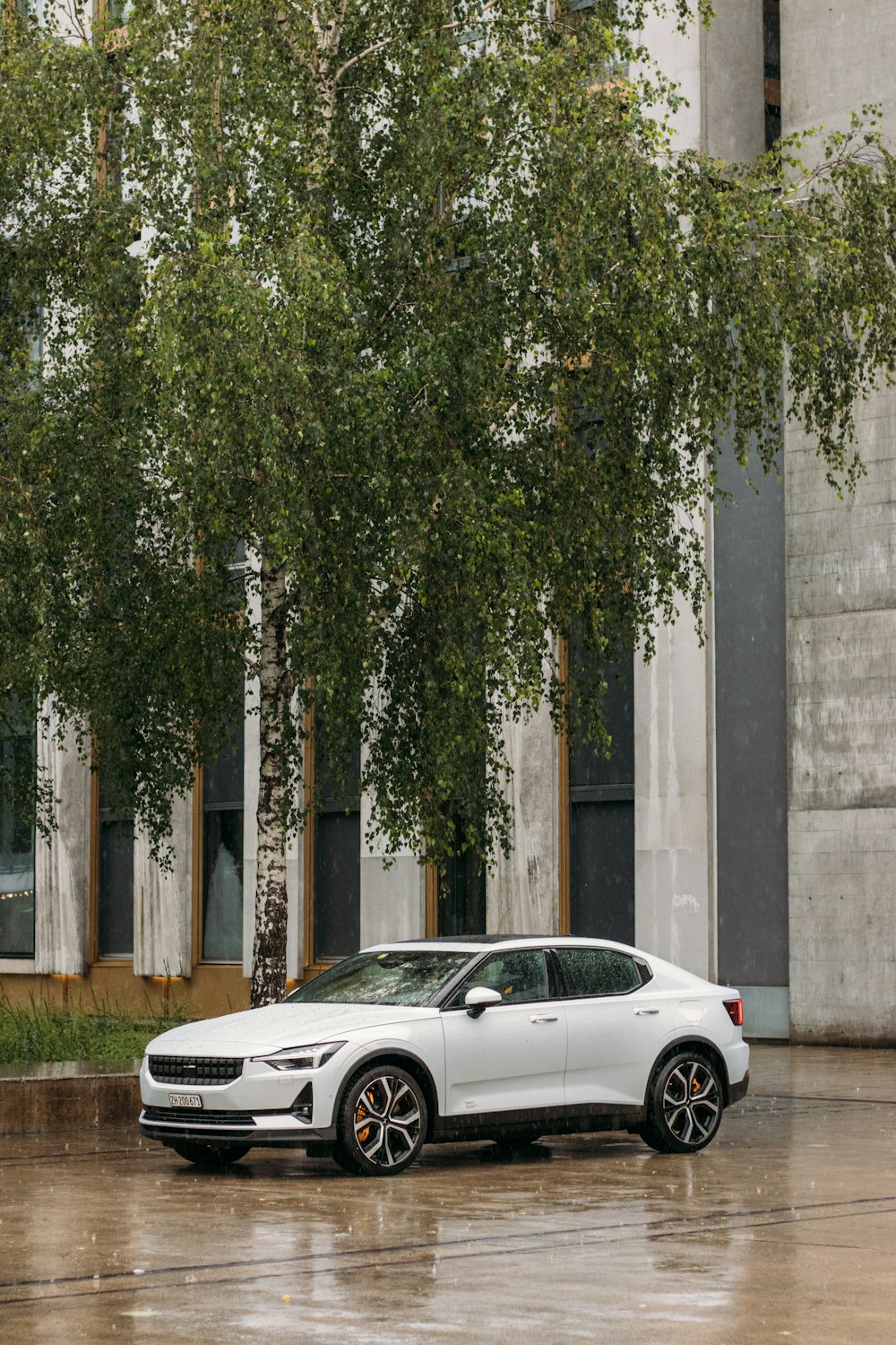 white coupe parked beside gray concrete wall during daytime