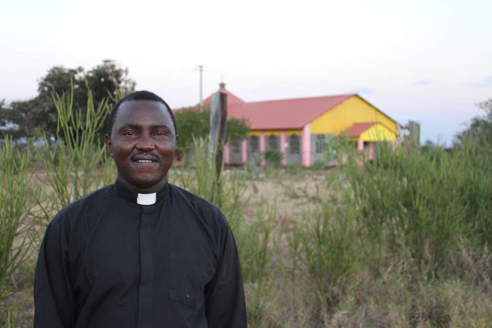 a man in a priest's outfit standing in front of a house