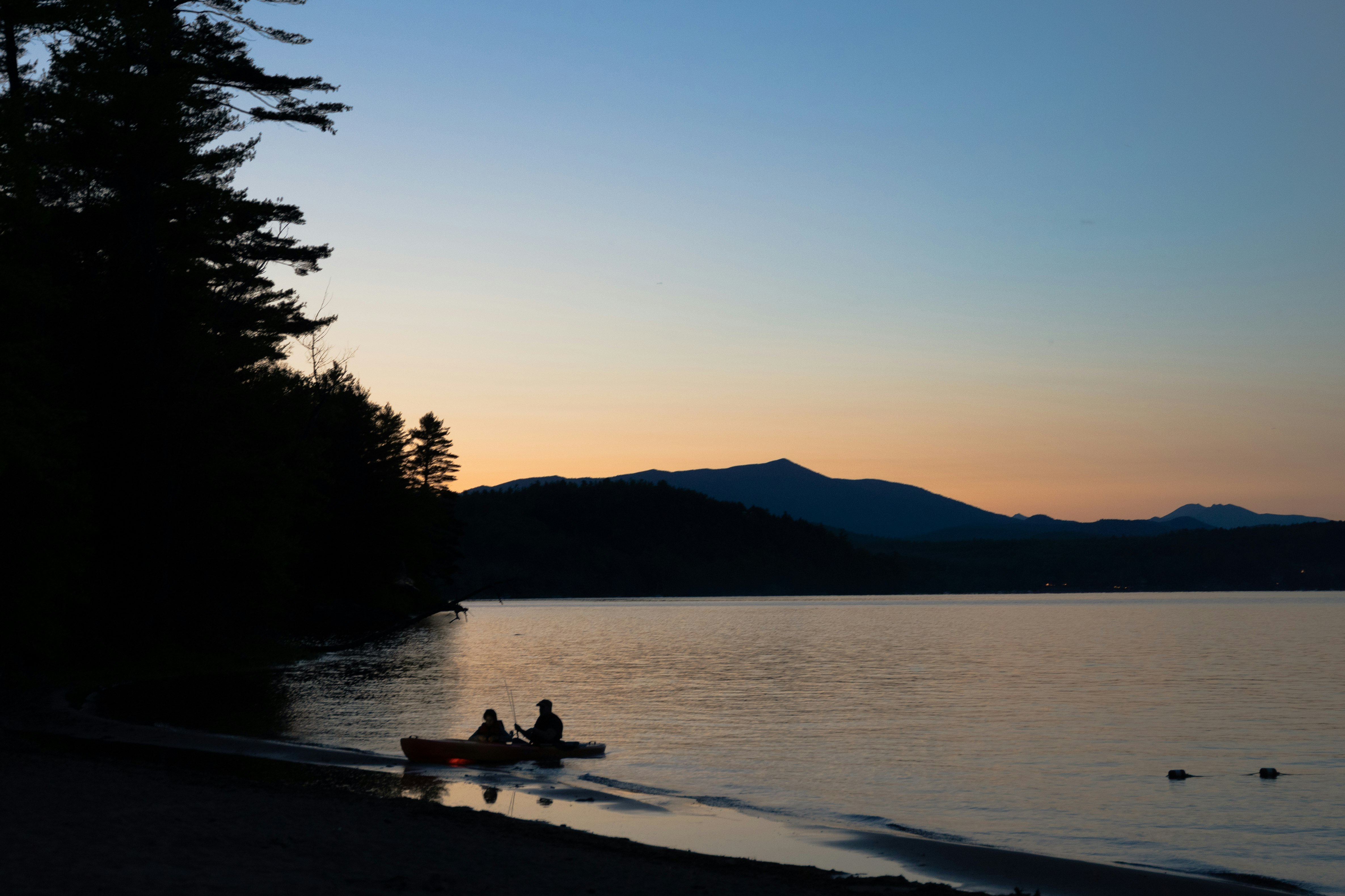 silhouette of people sitting on beach shore during sunset