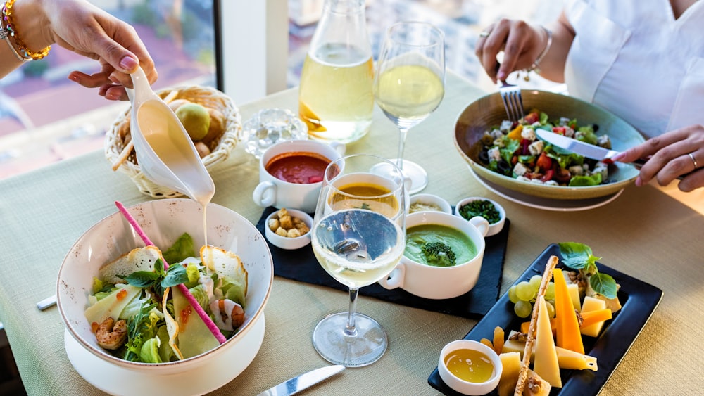 Ensalada de verduras en cuenco de cerámica blanca junto a copa de vino transparente