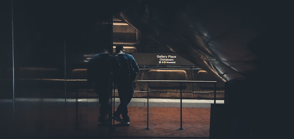 man in black jacket standing beside train rail