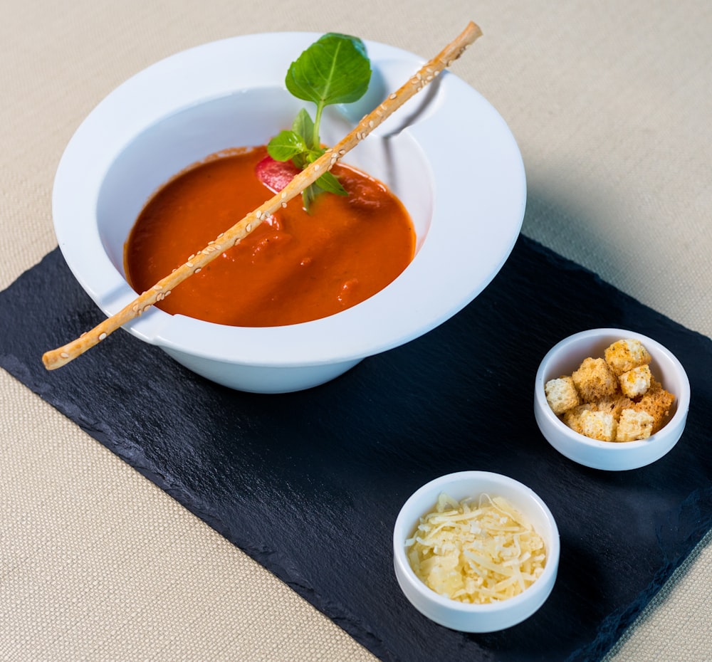 white ceramic bowl with soup and green leaf