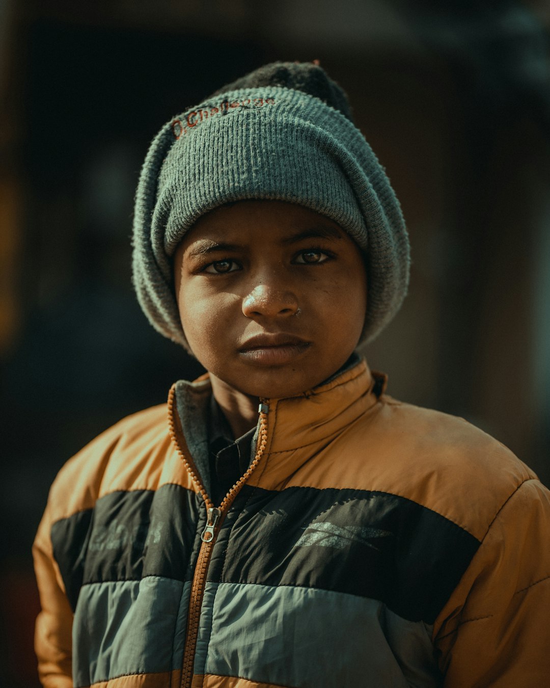 boy in black and brown zip up jacket wearing gray knit cap