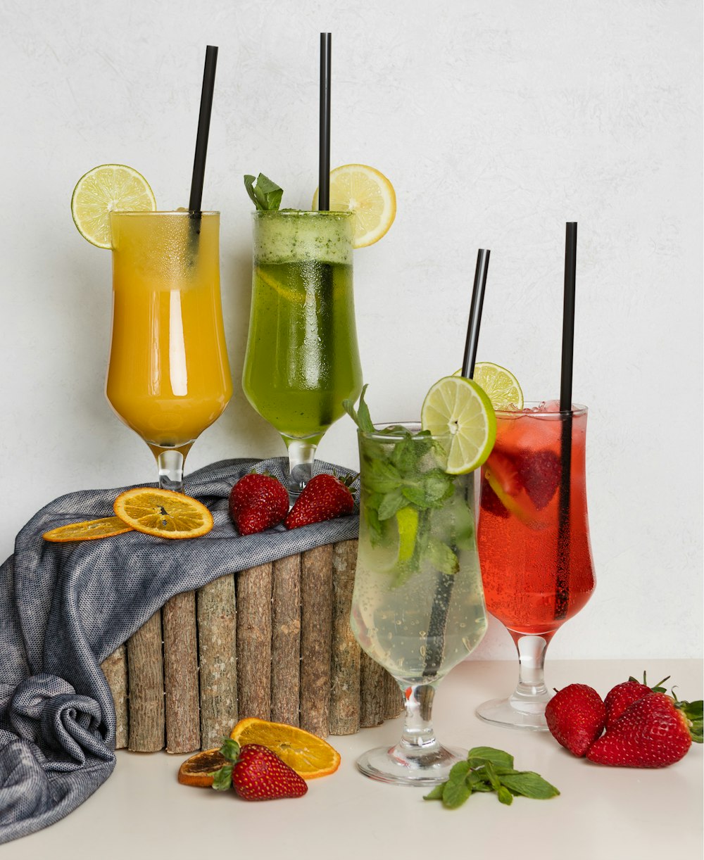 three clear wine glasses with yellow liquid and sliced lemon