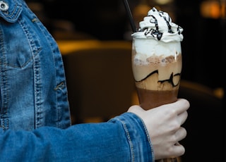 person in blue denim jacket holding ice cream cone with ice cream