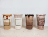 A lineup of clear PET cups in various sizes filled with iced coffee and smoothies on a café counter.
