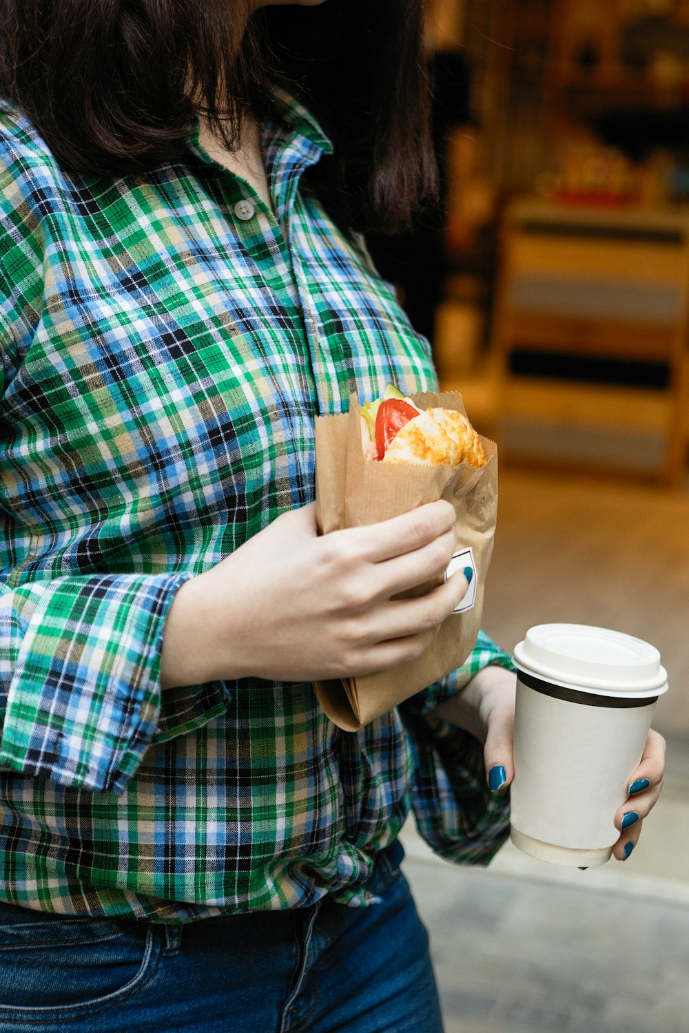 person in blue red and white plaid dress shirt holding bread
