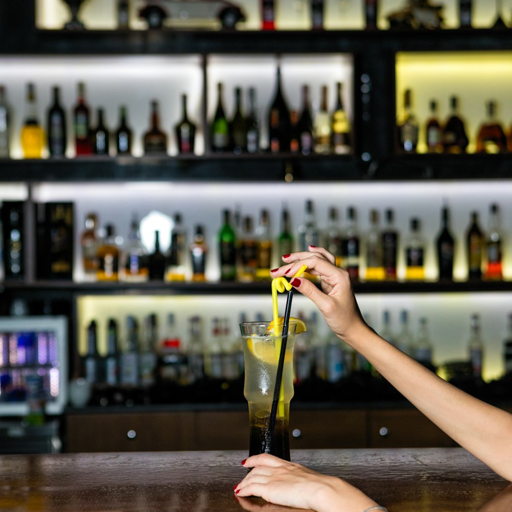 person pouring yellow liquid on clear glass bottle