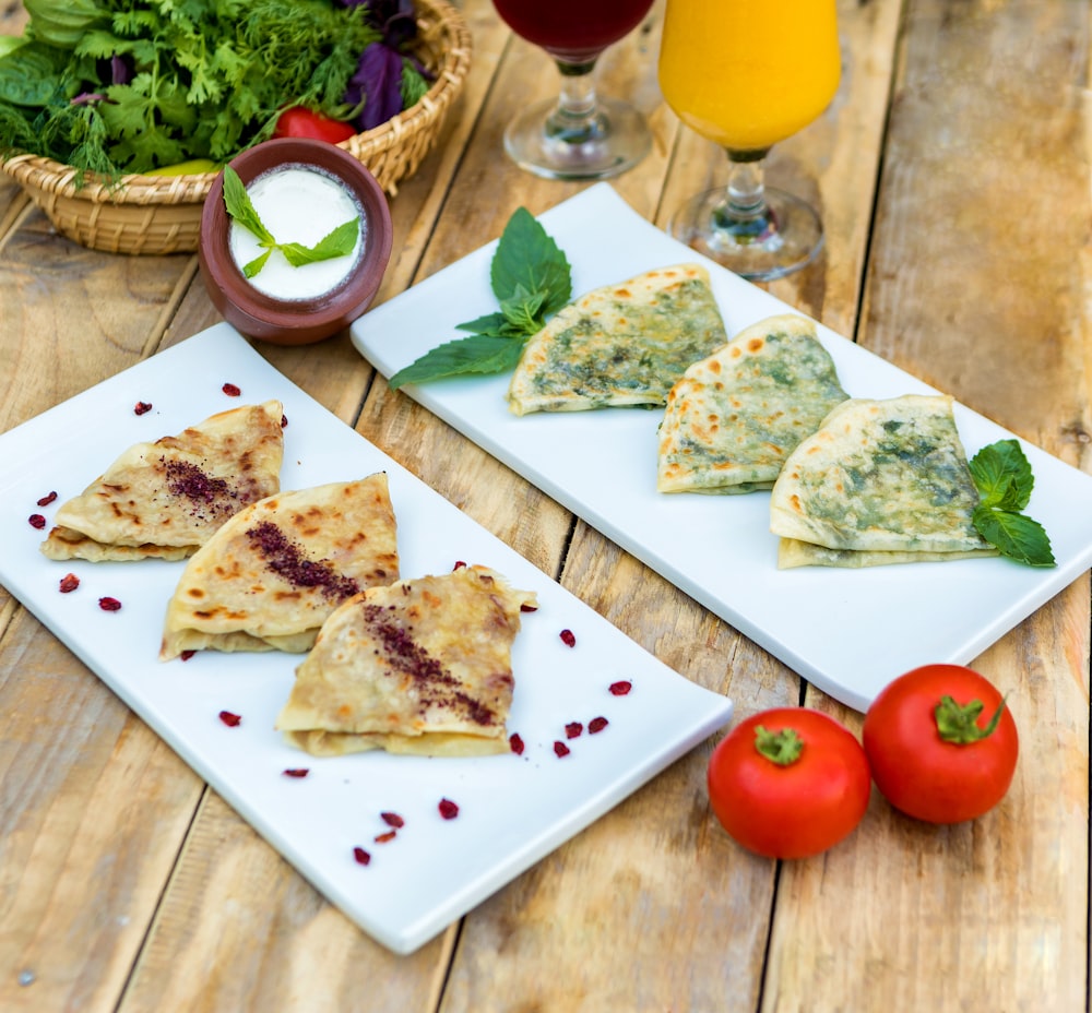 geschnittenes Brot mit geschnittenen Tomaten und grünem Gemüse auf weißem Keramikteller