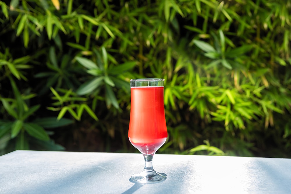 klares Weinglas mit roter Flüssigkeit auf weißem Tisch