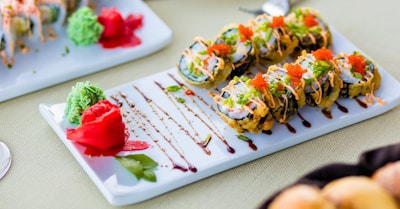 Elegant plating of sushi apanado with a drizzle of spicy mayo and tropical fruit slices.