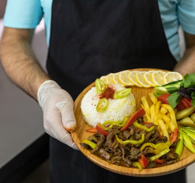 person holding brown round plate with burger