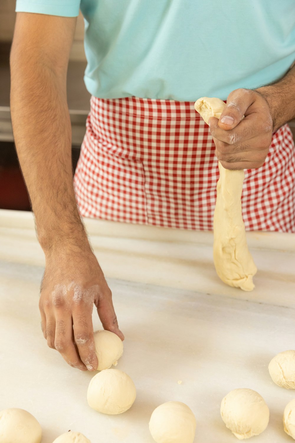 person holding white dough on white and red checkered textile