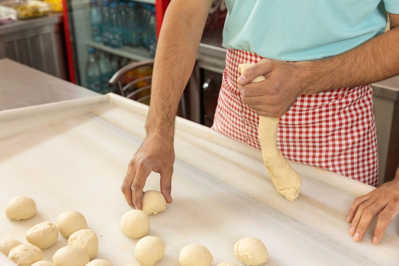 Hands sheeting fresh pasta dough on a floured board in an Italian kitchen