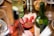An elegant spread of cured meats and sliced cheese is laid out on a wooden table. A small red bowl contains a relish or dip. The table also features bottles of wine and possibly sparkling water, along with polished cutlery and plates, suggesting a refined dining setup. The warm colors and soft focus create an inviting and cozy atmosphere.