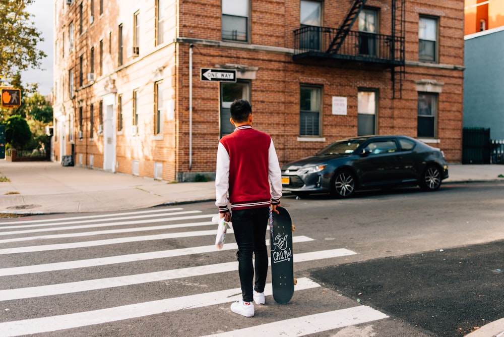 man in red and white long sleeve shirt and black pants walking on pedestrian lane during