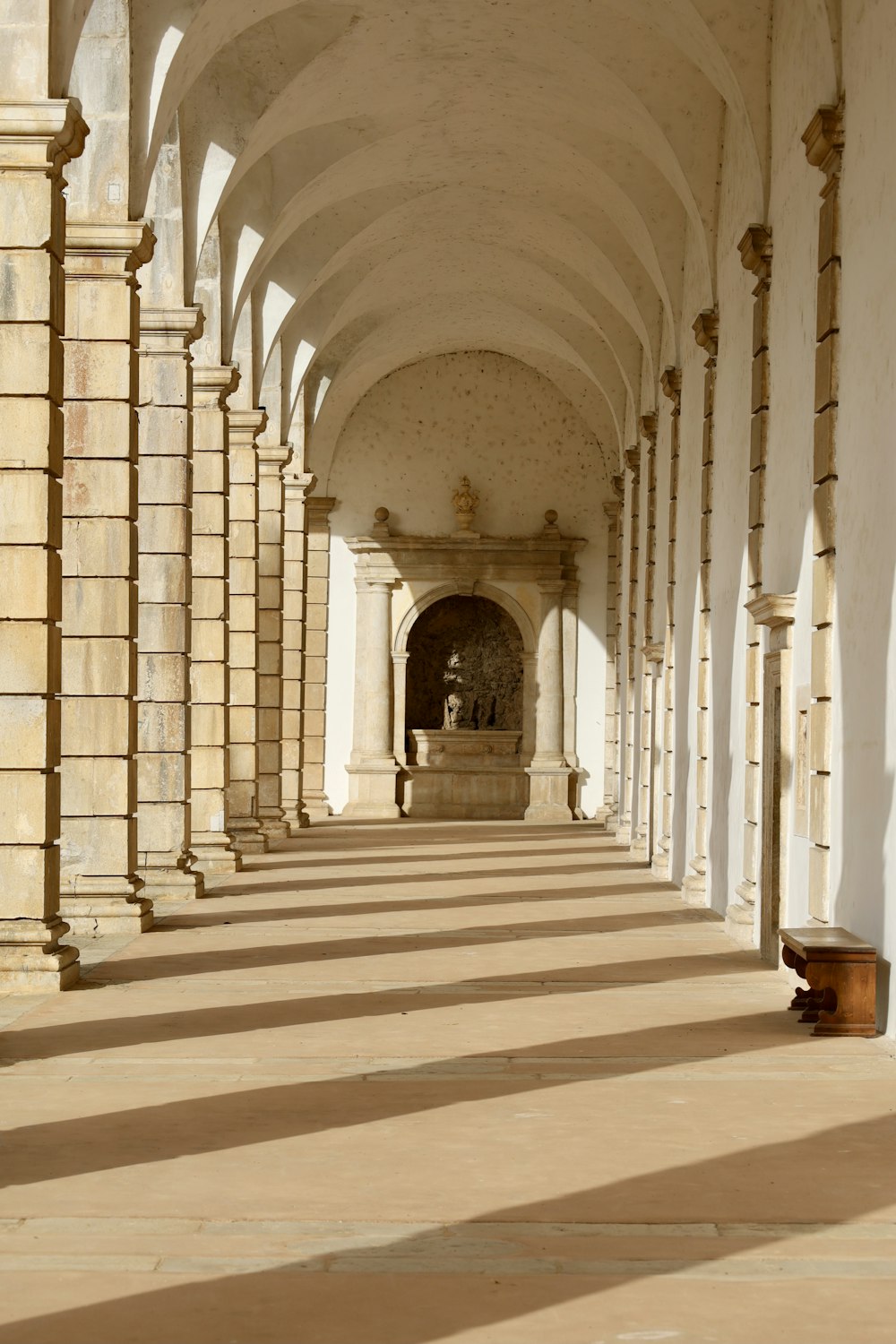 white concrete hallway with brown wooden benches