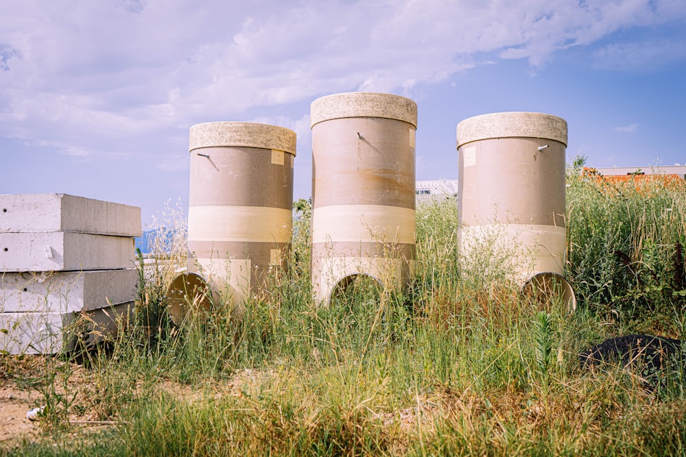 white and brown concrete barrels on green grass field under white clouds and blue sky during