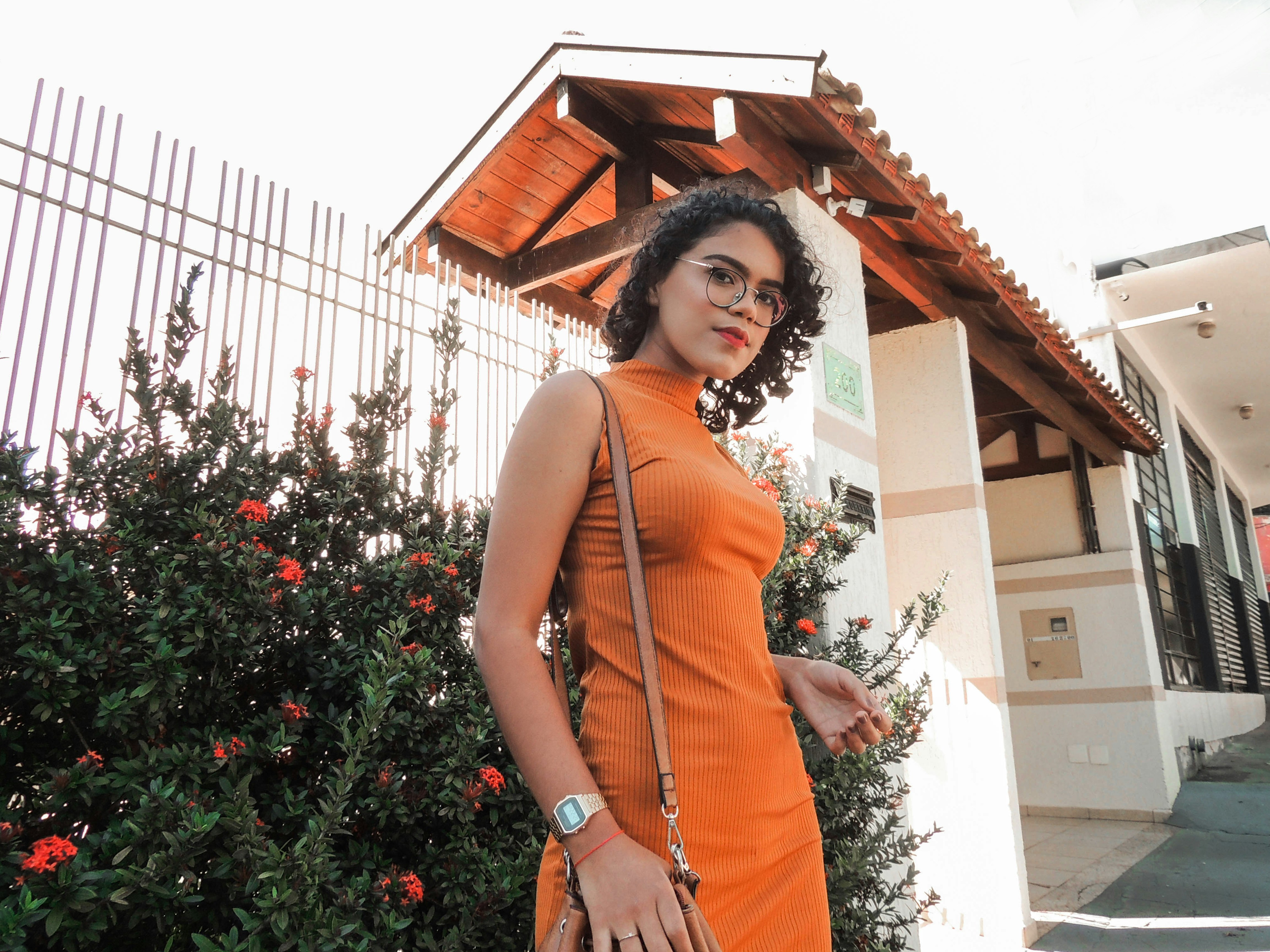 woman in orange sleeveless dress standing near green plants