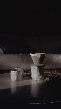 A cozy kitchen scene featuring bright, hand-thrown stoneware mugs and bowls arranged on a wooden table with soft natural light.