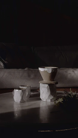 Sunlight casting soft shadows over a set of handmade stoneware cups and bowls on a table.
