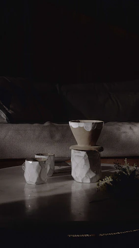 A cozy scene featuring hand-painted ceramic cups and sleek tumblers arranged on a wooden table.