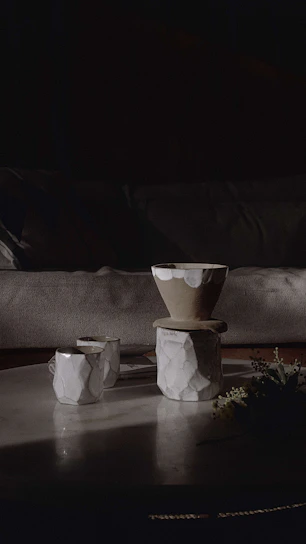 A cozy kitchen scene featuring bright, hand-thrown stoneware mugs and bowls arranged on a wooden table with soft natural light.