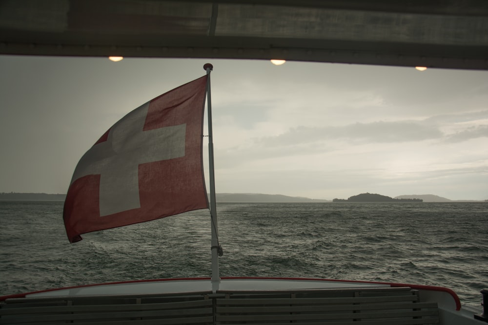 rot-weiße und schwarze Flagge auf weißem Metallmast in der Nähe des Meeres tagsüber