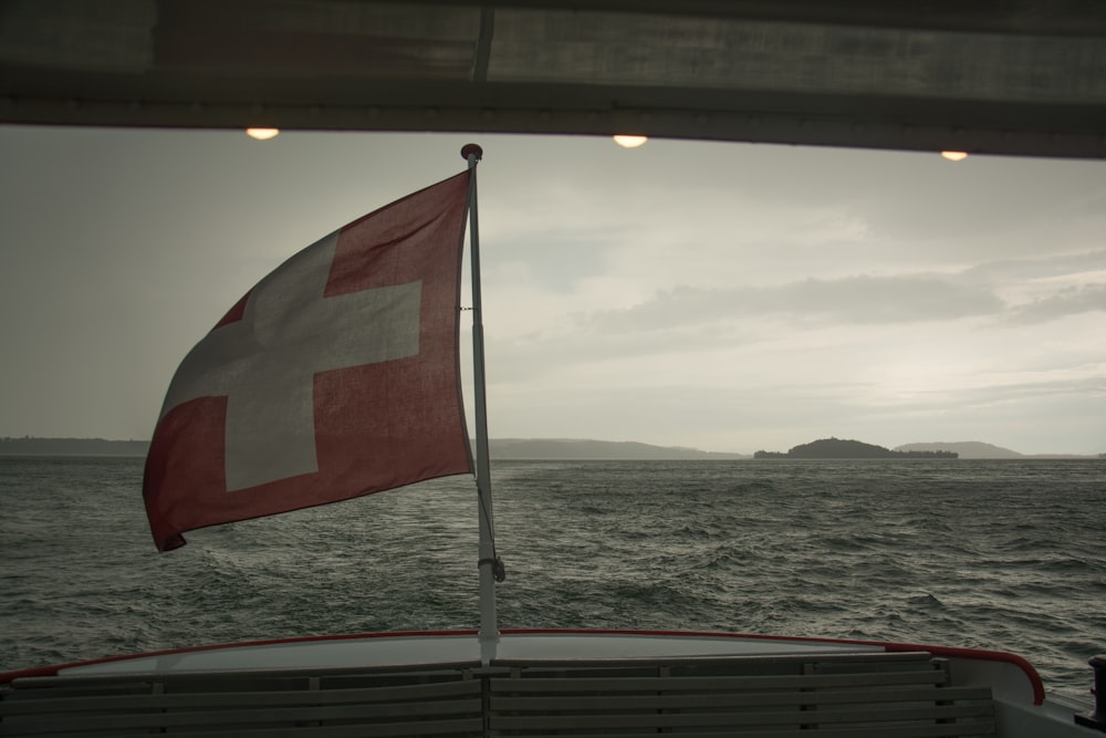 red white and black flag on white metal pole near sea during daytime