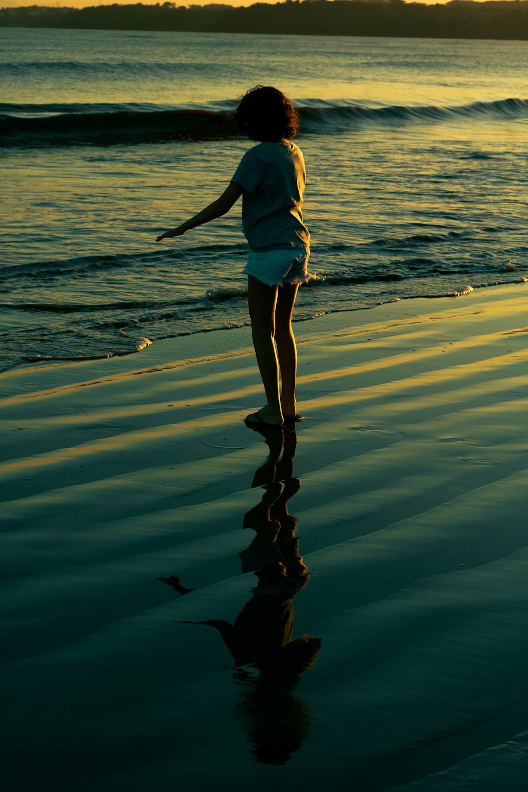 woman in white shirt and white shorts standing on seashore during daytime