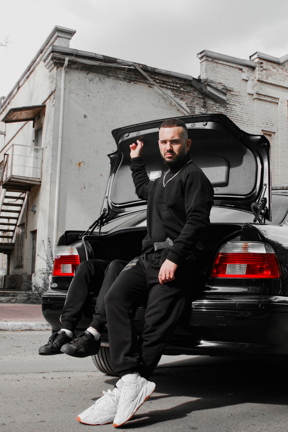 man in black jacket sitting on black car
